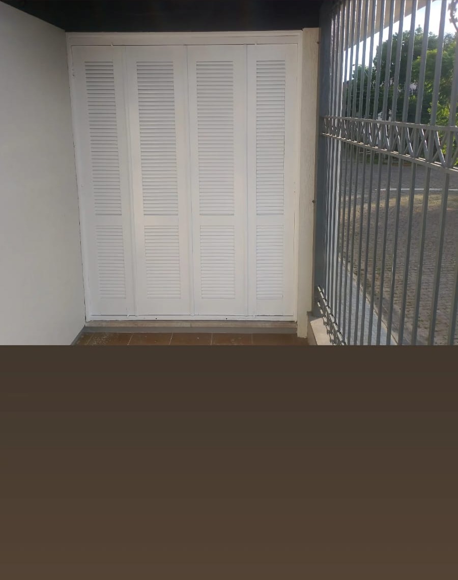 armário embutido com quatro portas de veneziana brancas em varanda com grade metálica e vista de rua de parale